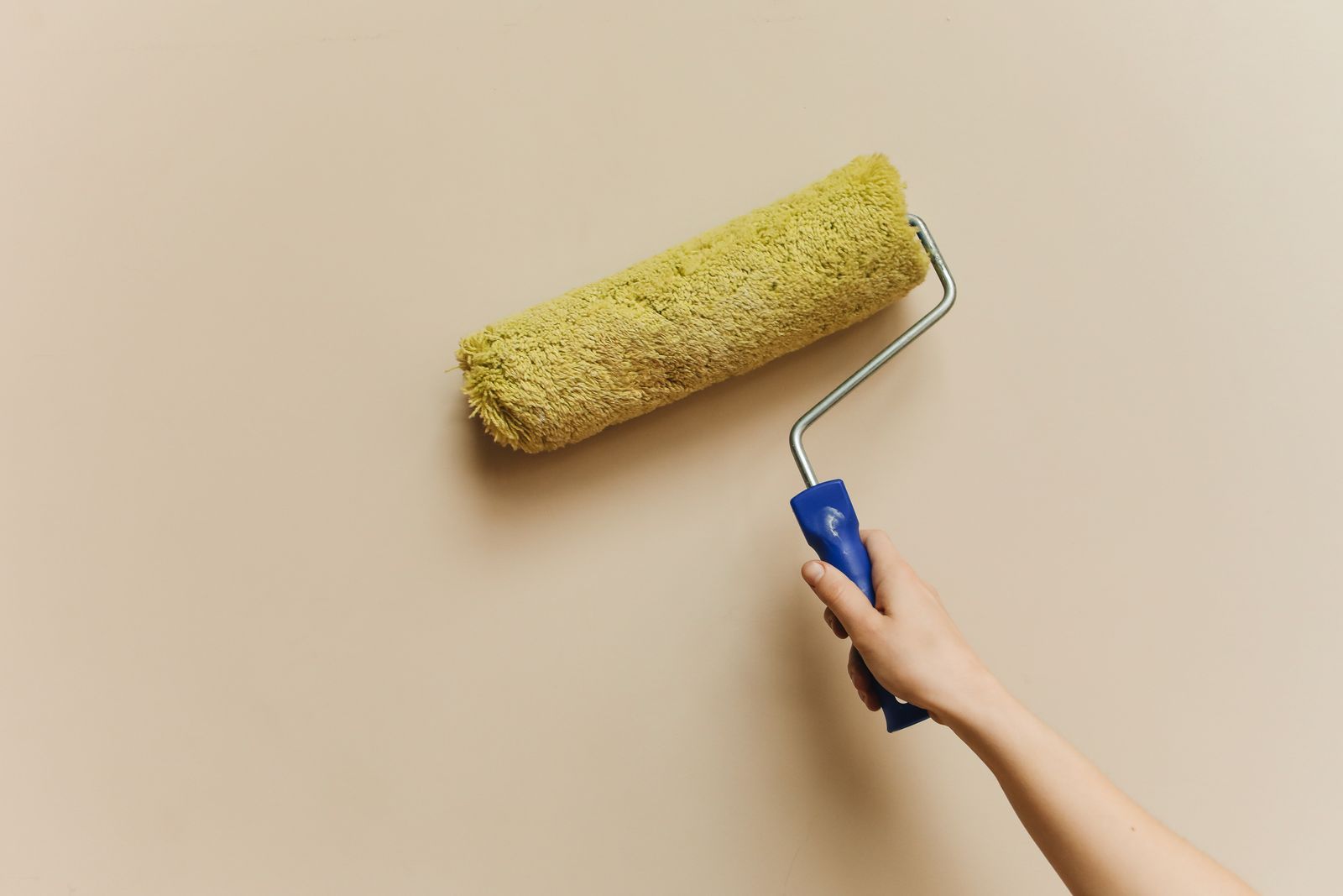 Hand mit Farbrolle an der Wand